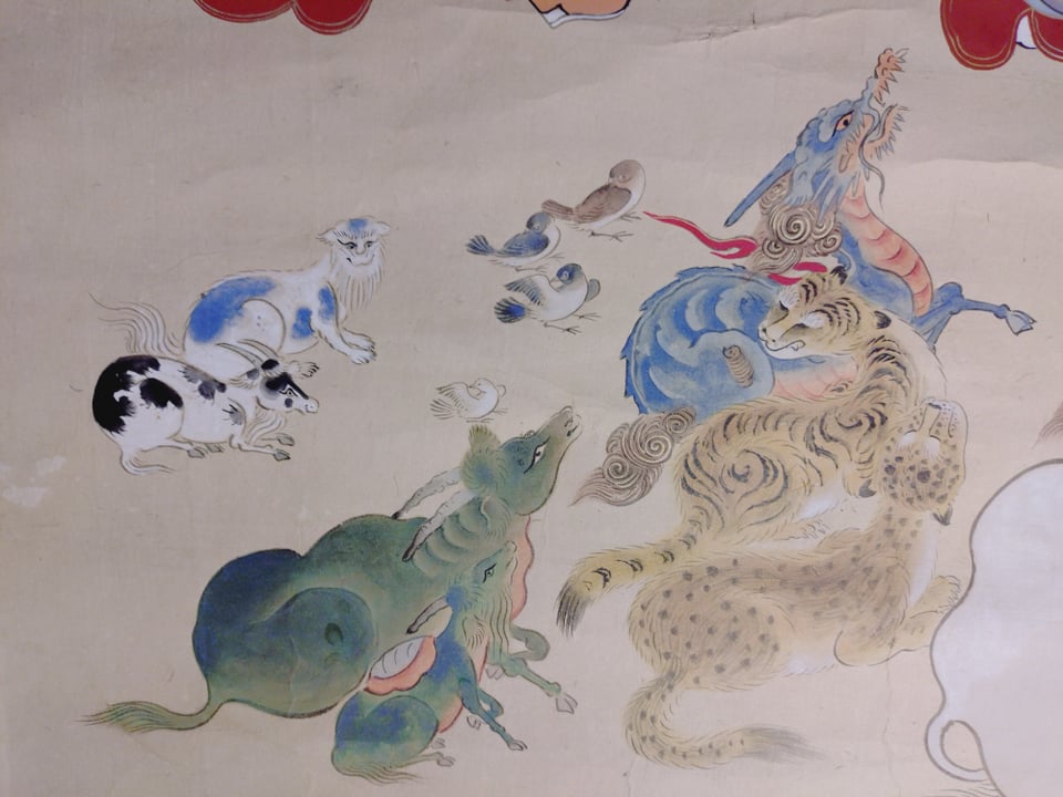 涅槃図左下、白地に青模様の動物が猫です。